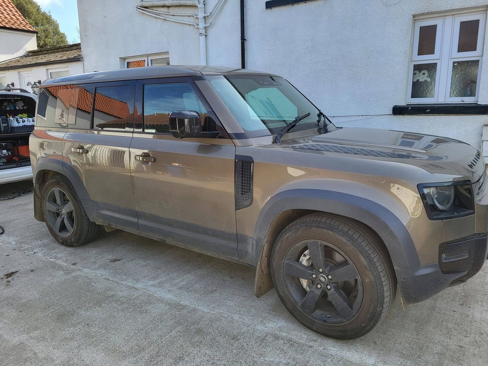 A large four-wheel drive before valeting, its lower doors, sills and wheels caked in dried lane mud